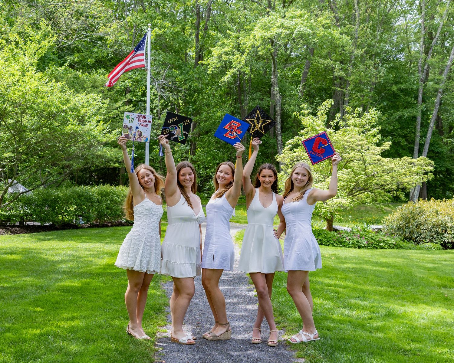 Graduates in bright blue caps and gowns celebrating on a lawn in front of a brick building.