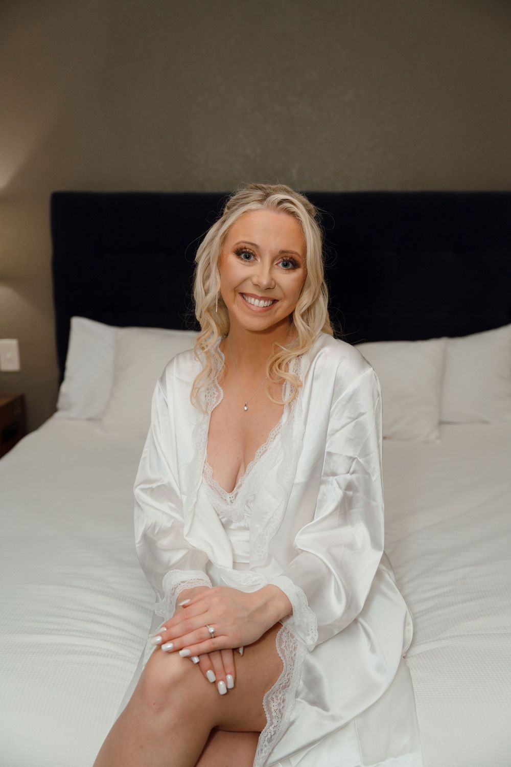 A series of boudoir photos showing someone in a white silk robe posing on a bed with white linens.