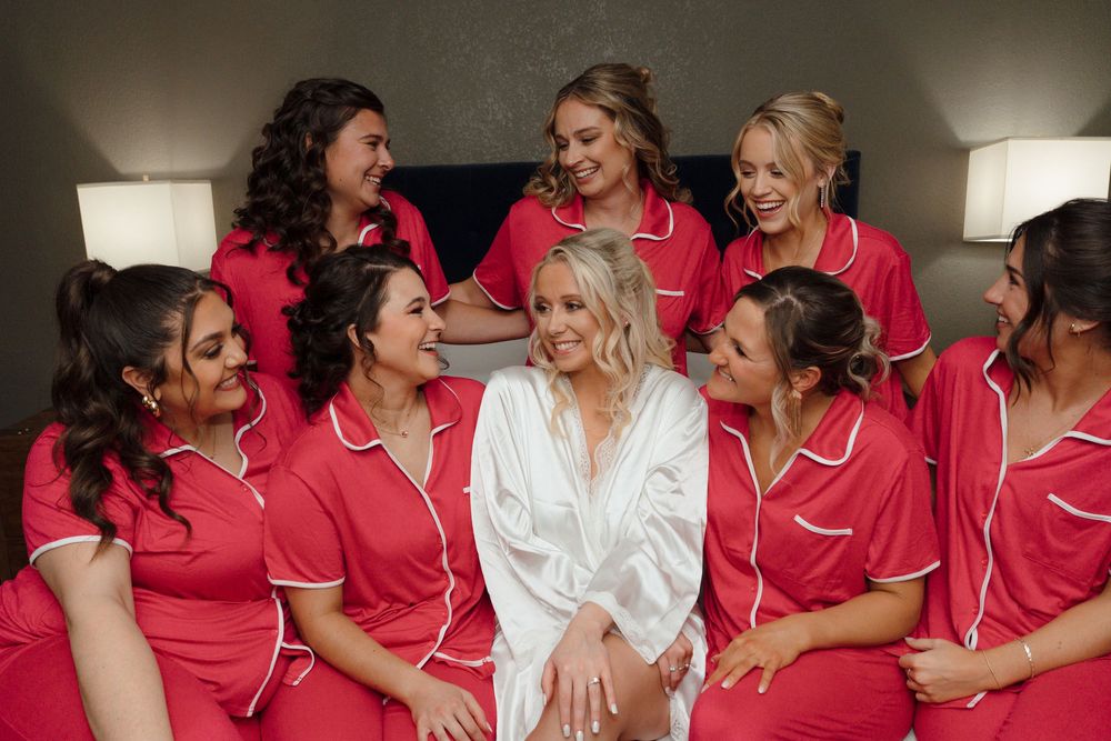 Bridesmaids in matching pink satin robes gathered together for pre-wedding photos.
