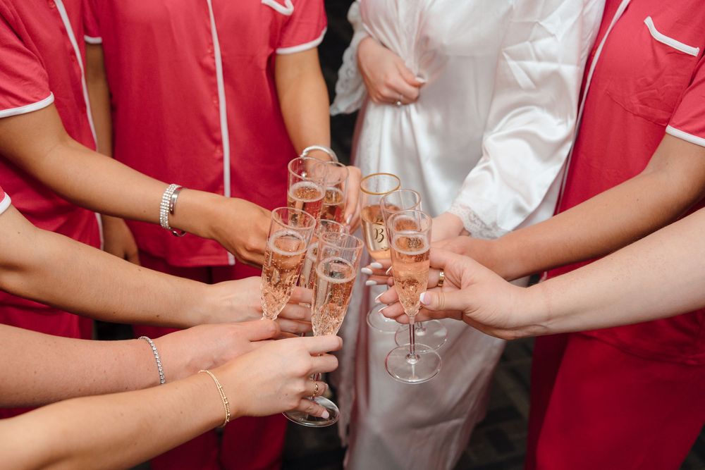 Wedding party members in red and white attire toasting with champagne glasses.