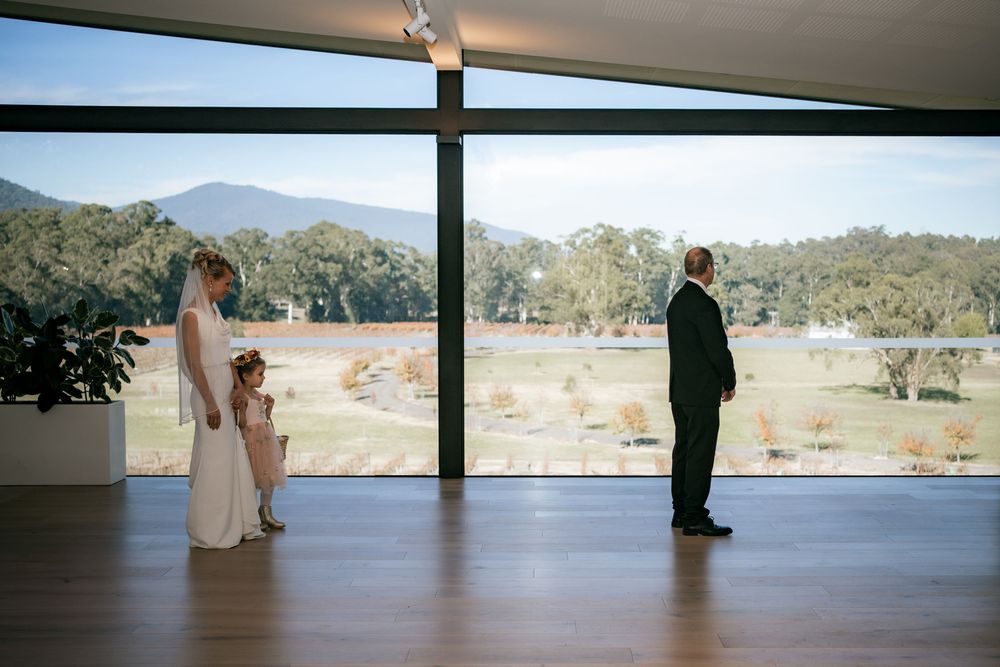 Wedding ceremony silhouettes against floor-to-ceiling windows overlooking a scenic lake and mountains.