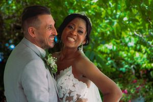 Happy interracial couple smiling closely together outdoors on their wedding day.