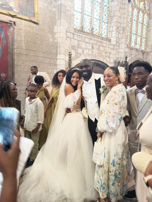 Bride and groom pose with guests inside a church during a wedding ceremony, bride wearing an elegant white off-shoulder gown.