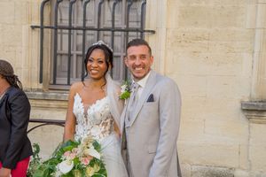Smiling bride and groom posing together outside a stone church on their wedding day.