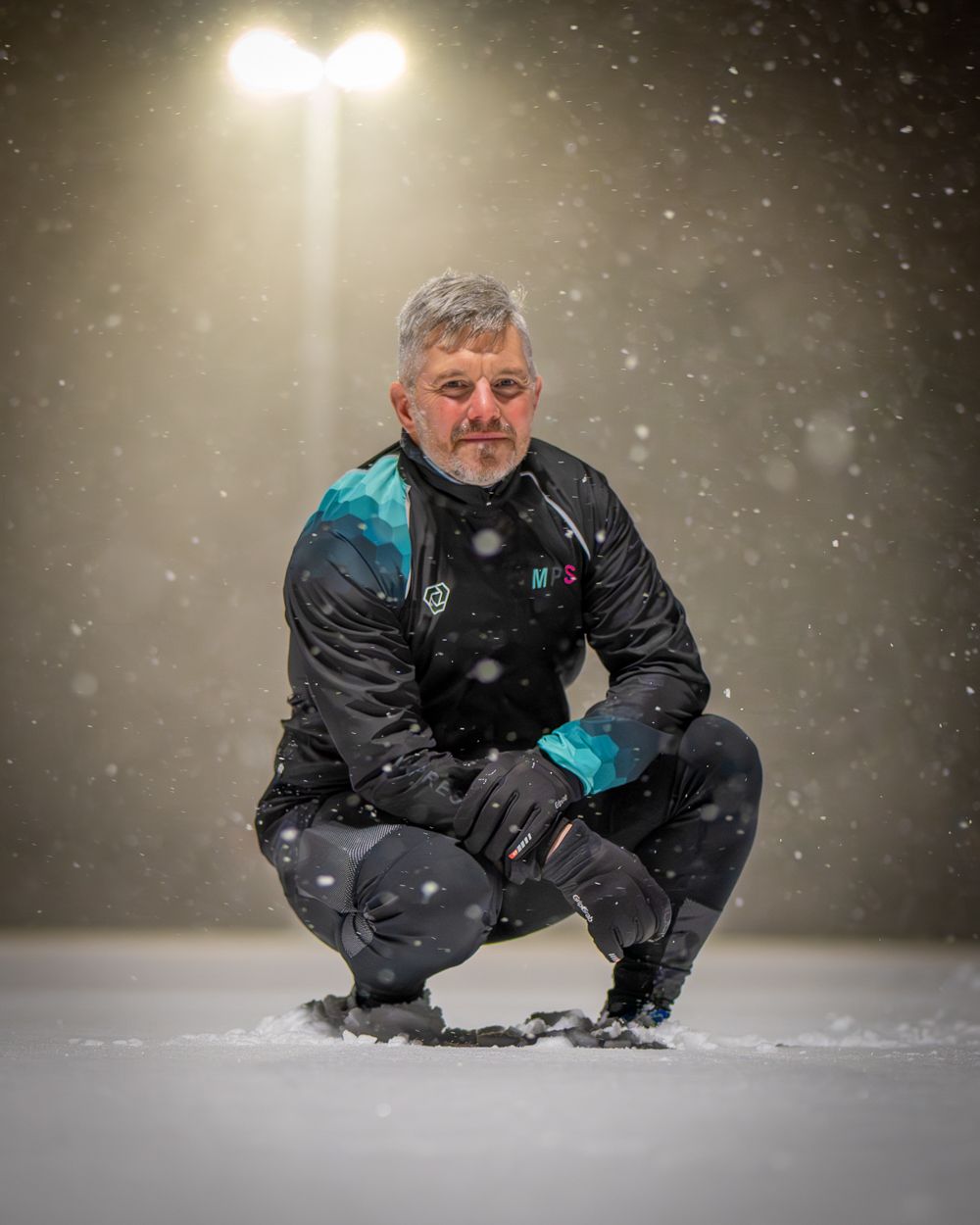 Mäktigt porträtt på en person som sitter på huk i ett snörikt landskap.