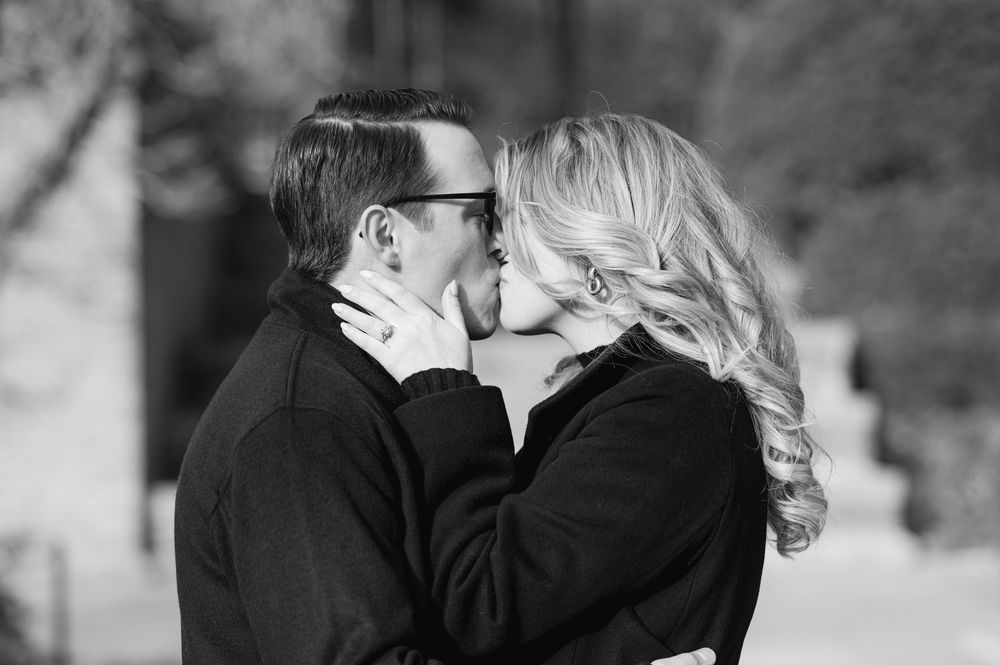 Romantic black and white photo of a couple sharing a kiss outdoors.