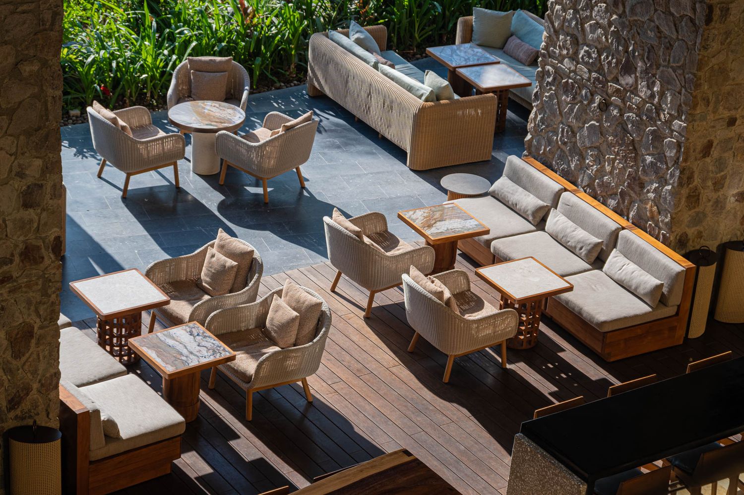 Luxury tropical resort terrace with palm trees, ocean views, and elegant outdoor seating under a wooden pergola.
