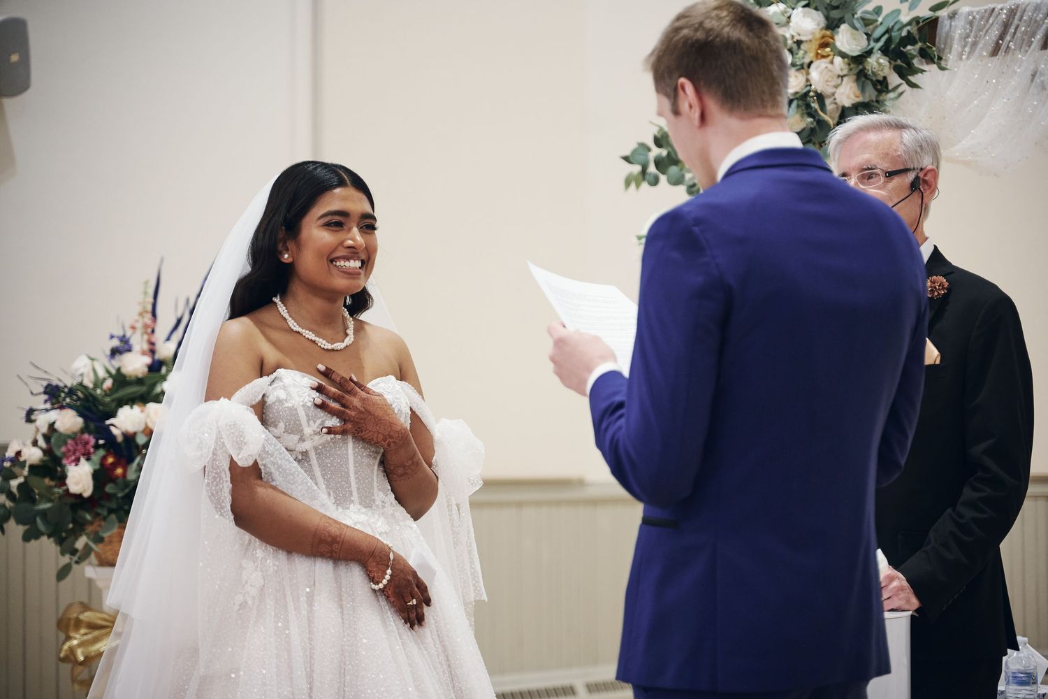 Man in suit placing ring on smiling woman's finger outdoors, romantic engagement moment.