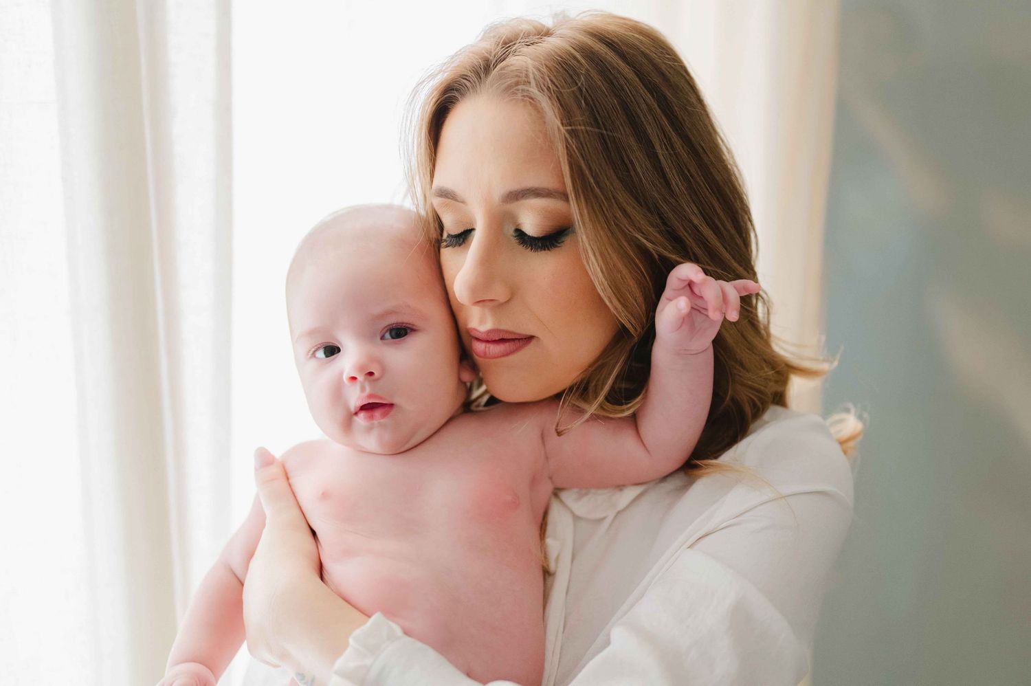 Nel giorno del Battesimo a Palermo una Mamma tiene in braccio per le foto a casa suo figlio, trucco make up artist.
Battesimo Altavilla