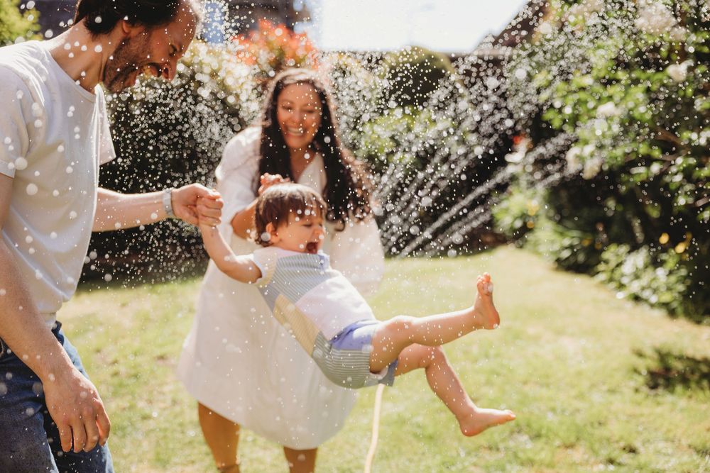 Playful summer scene with water splashing and laughter in a sunny backyard garden.