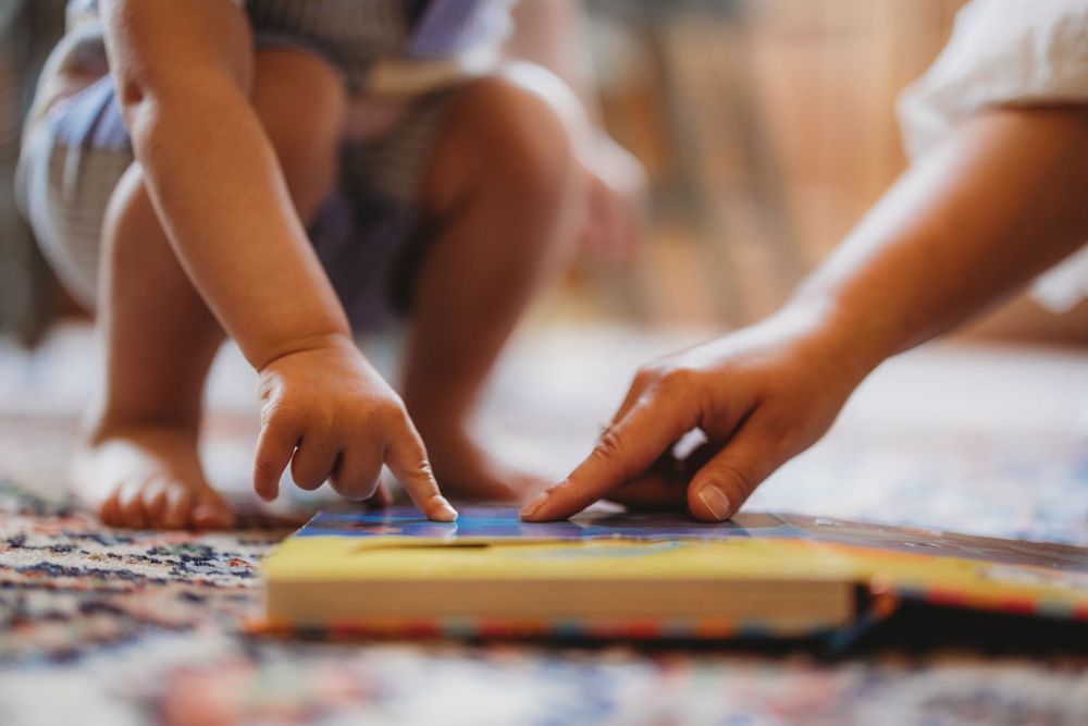 Close-up view of hands working on a colorful jigsaw puzzle spread out on a wooden table.
