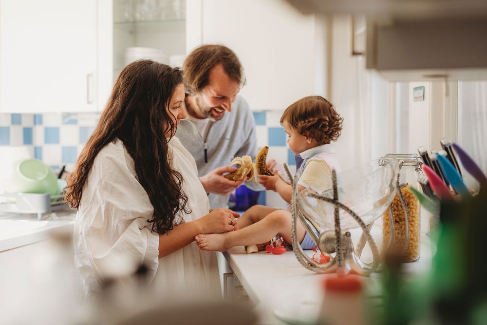 Family of three sharing a joyful morning moment in a bright kitchen, with parents and child bonding over breakfast.