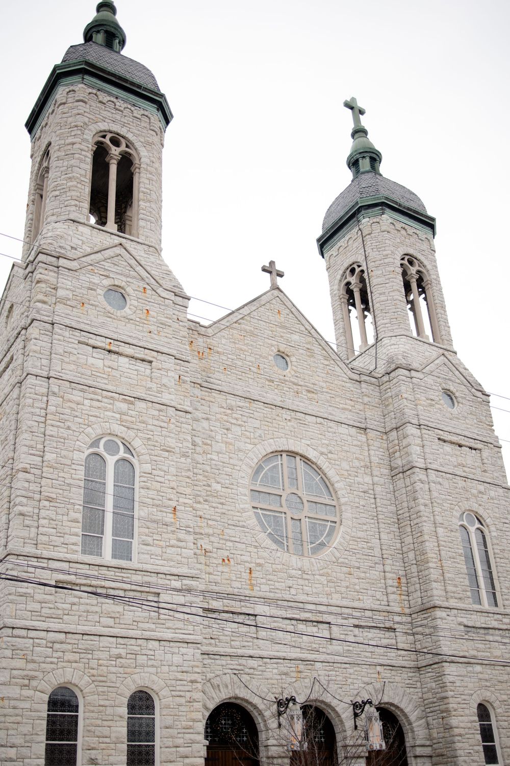 Historic stone church with twin bell towers, arched windows, and crosses against an overcast sky.