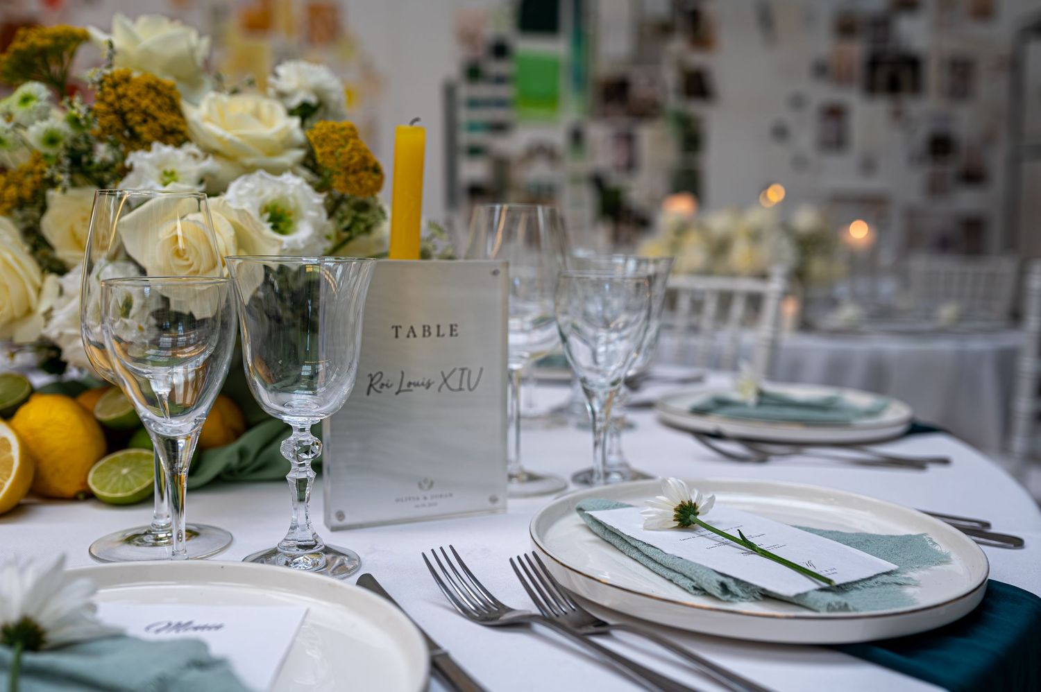 Cadre de table de mariage élégant avec des fleurs blanches, des citrons, des serviettes vertes, de la verrerie et une carte de numéro de tab
