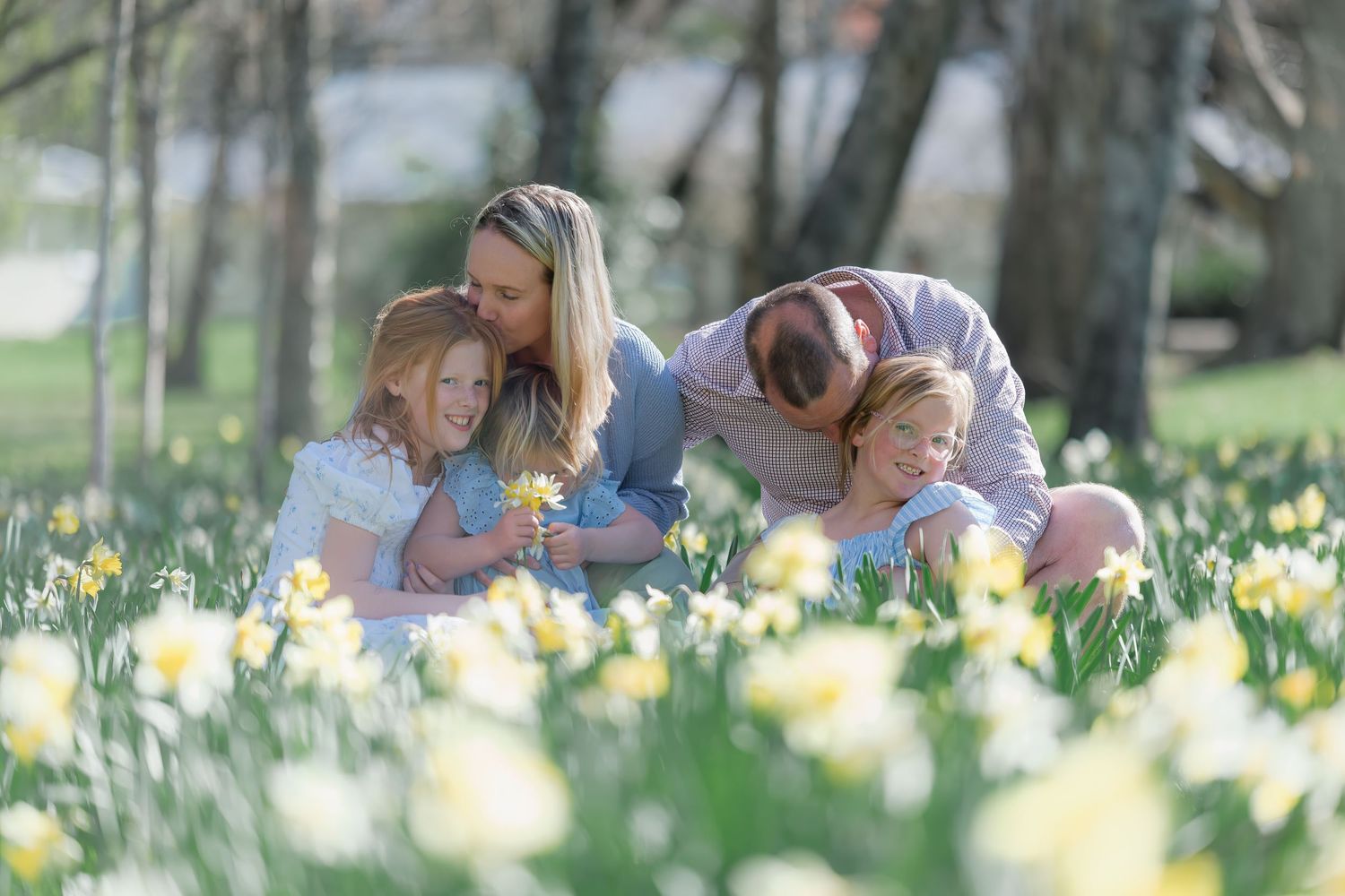 Large multigenerational family posing outdoors in neutral tones for a portrait near a historic brick building.