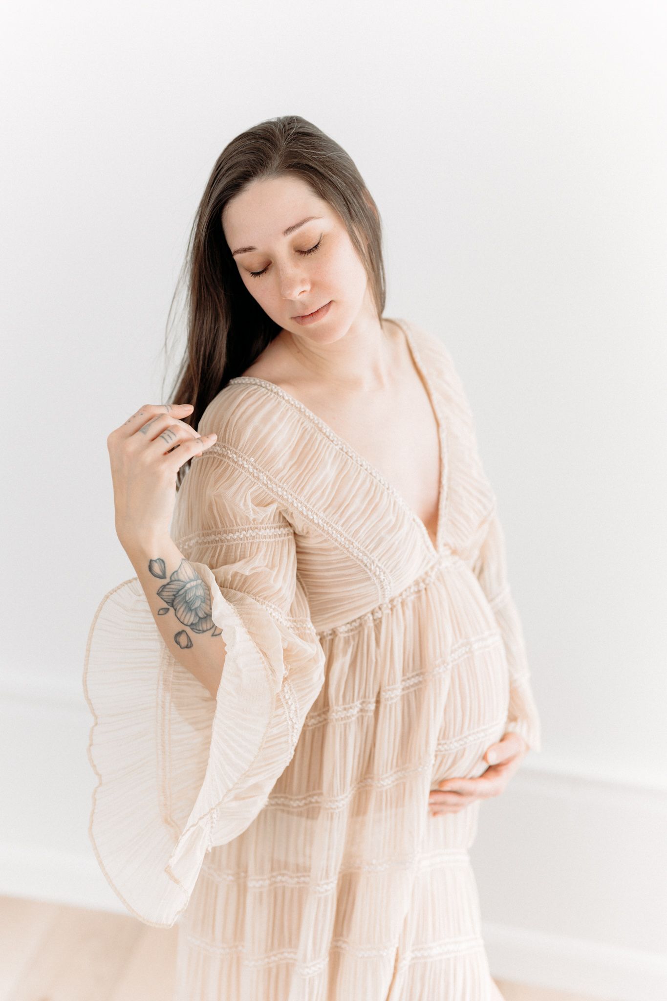 Future maman dans une robe beige en tulle vaporeux de la garde-robe cliente pour une séance maternité fine art au studio de Québec