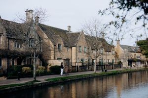 Charming Cotswolds village with honey-stone cottages lining a calm river on a peaceful winter day at Bourton on the water.