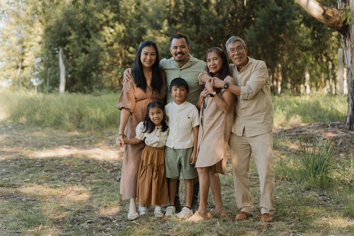 Multi-generational family smiling together outdoors in a green park for a portrait. Family photoshoot in Rouse hill regional park