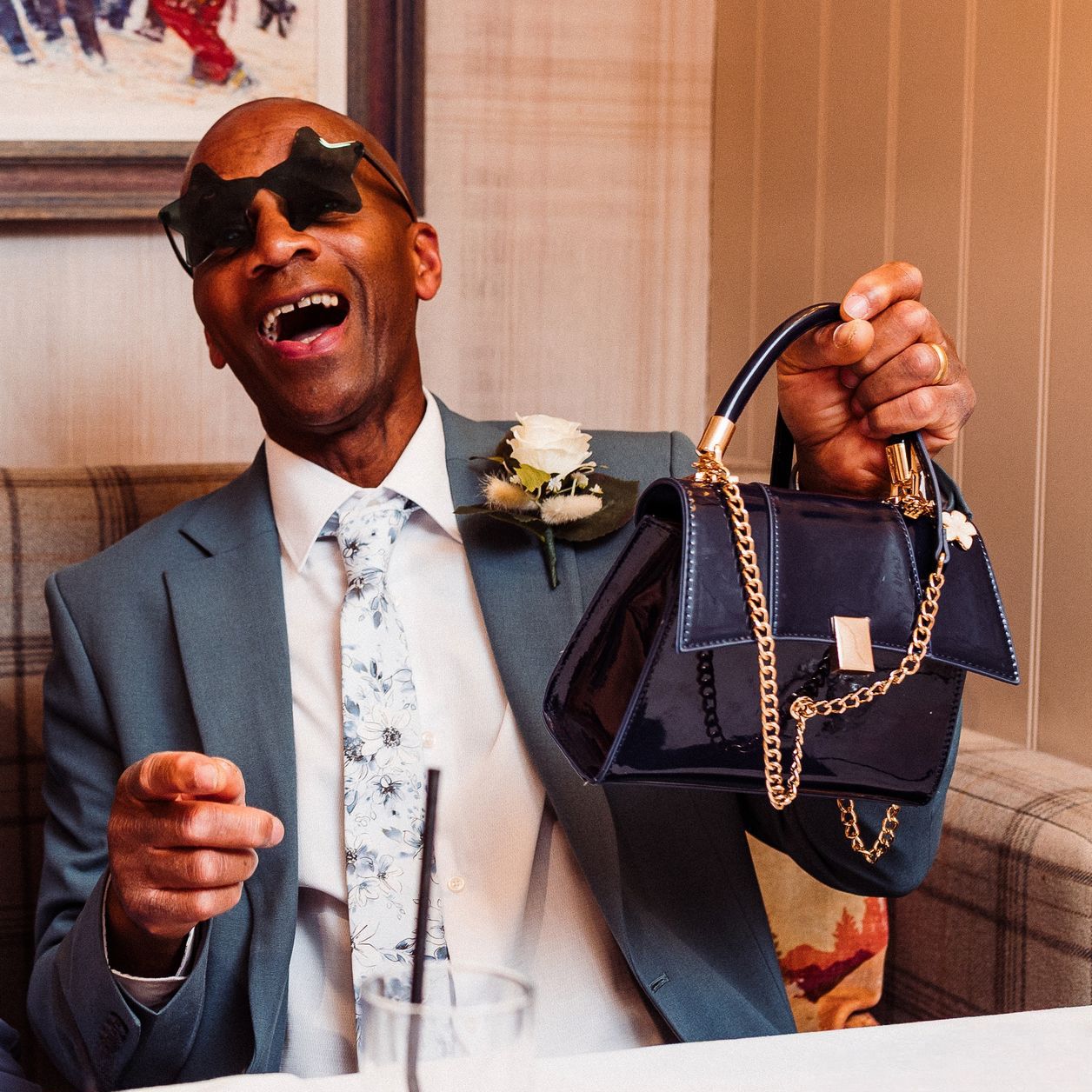 Man at a wedding with a woman's handbag and star shaped glasses