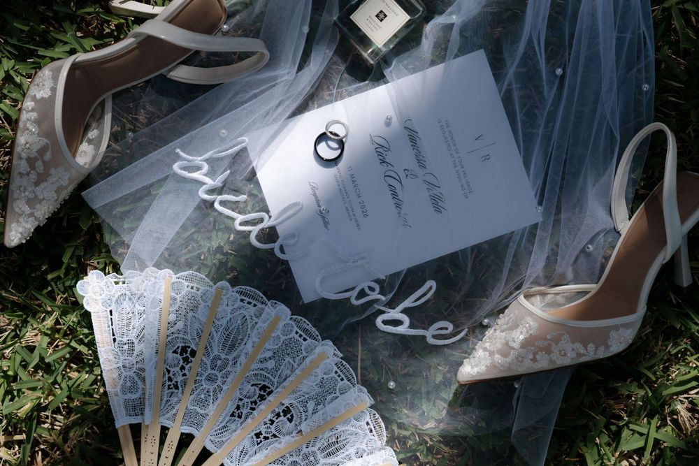 Bridal accessories including shoes, rings, invitation, and fan styled on the grass at Majestic Elegance Costa Mujeres wedding.