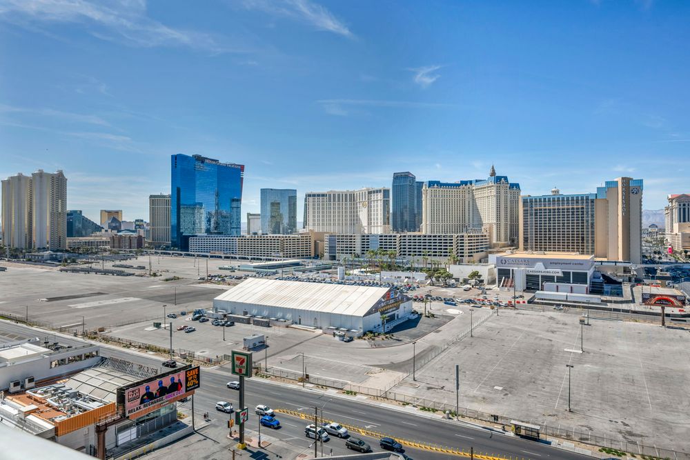 Aerial view of the Las Vegas Strip with large casino hotels and open lots on a sunny day.