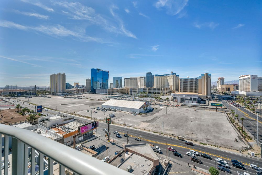 Aerial view from a balcony overlooking the Las Vegas Strip with casinos and open land.