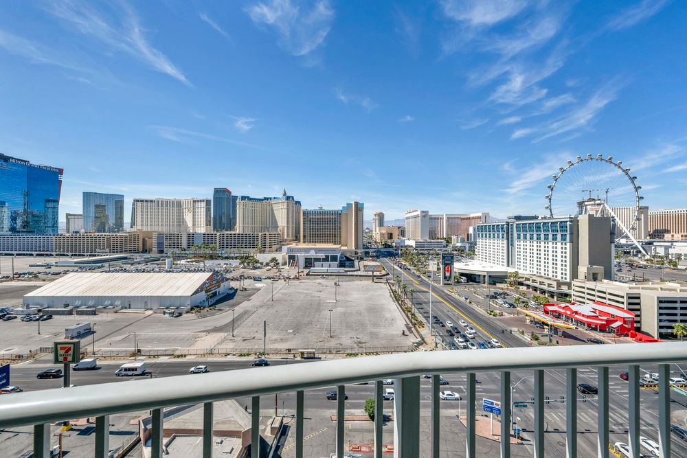 Panoramic Las Vegas Strip skyline view from a high-rise balcony featuring the High Roller Ferris wheel.