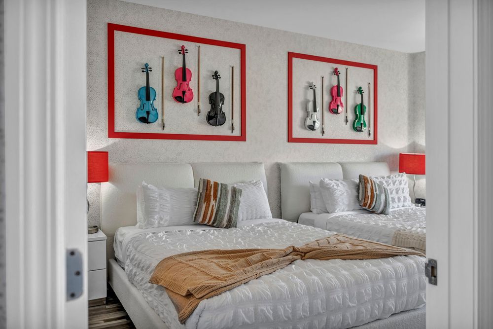 Elegant hotel bedroom with twin beds and colorful violin wall art in red-framed displays.