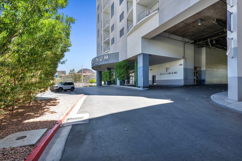 The Platinum Hotel entrance driveway with shaded canopy and lush green trees in Las Vegas.