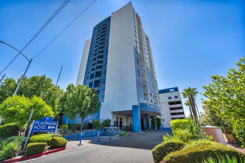 The Platinum Hotel high-rise tower surrounded by palm trees under a bright blue Las Vegas sky.
