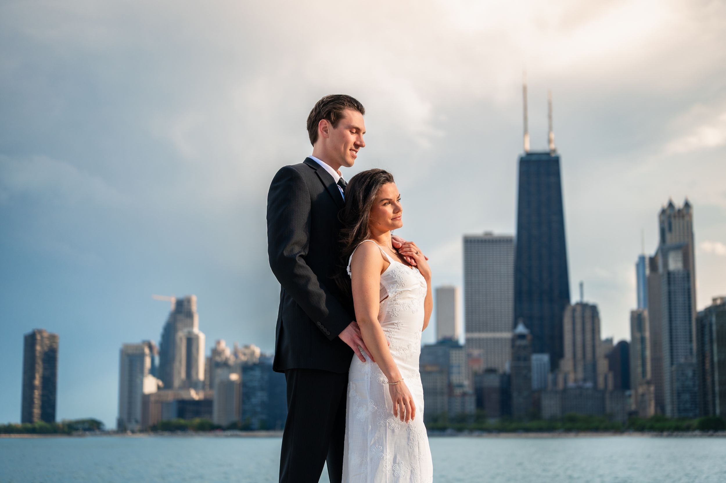 Bride and groom pose romantically with Chicago skyline and John Hancock Center in background on their wedding day.