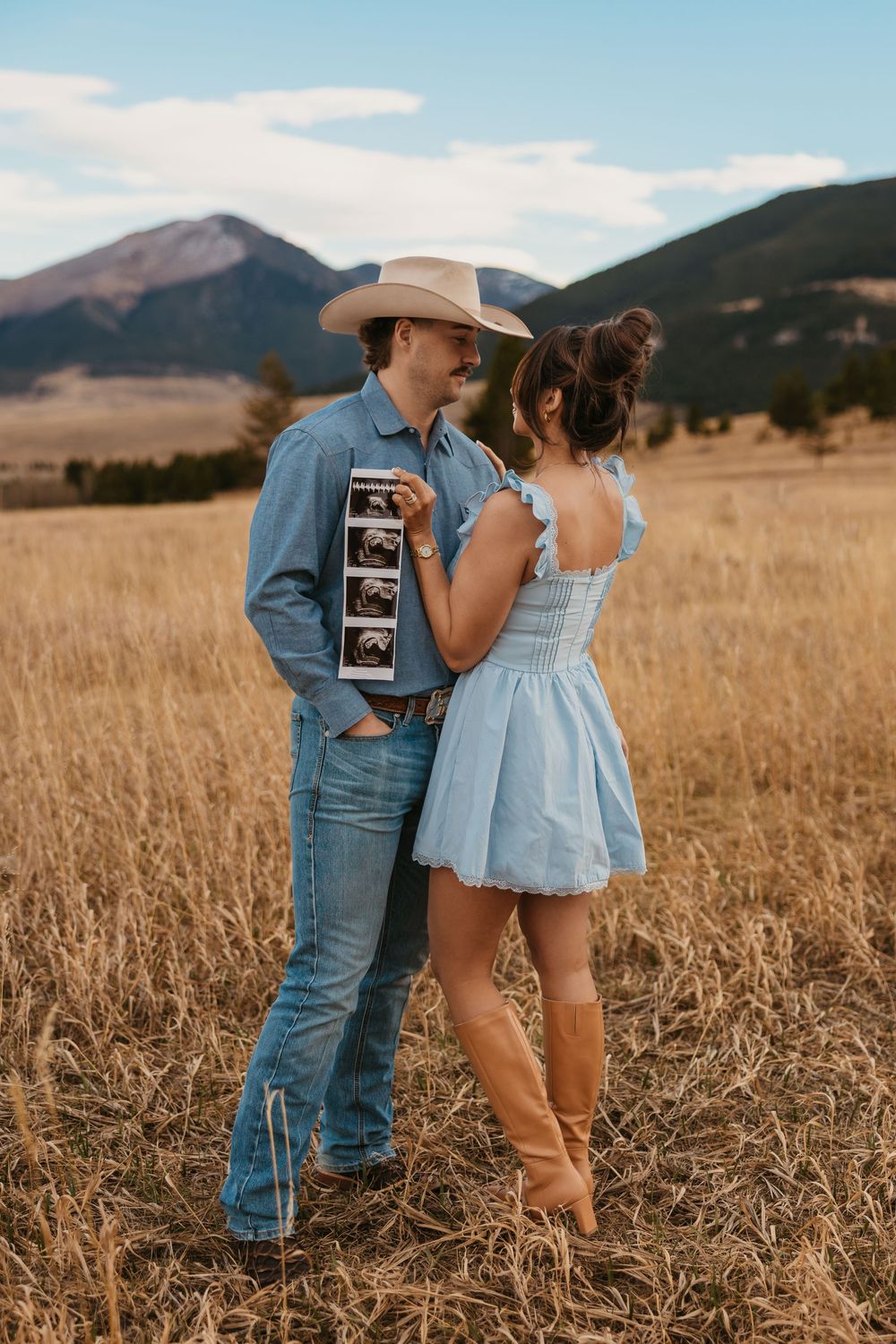 Cowboy holds wife while showing off ultrasound photos in the mountains of Red Lodge, Montana captured by Montana Photographer
