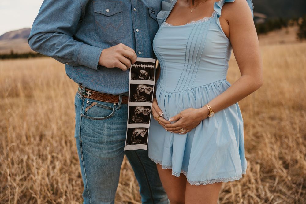 Cowboy holds wife while showing off ultrasound photos in the mountains of Red Lodge, Montana captured by Montana Photographer