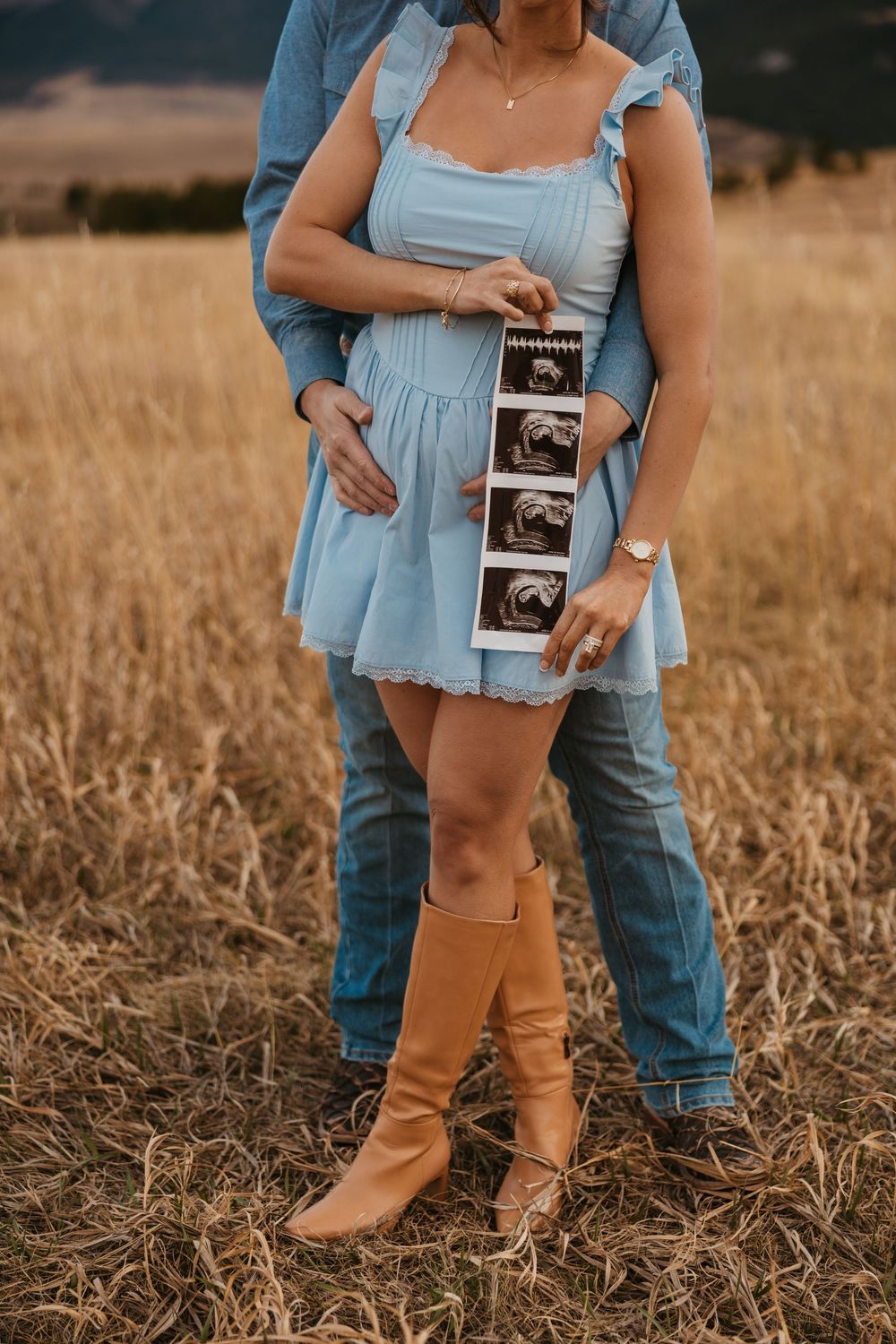 Cowboy holds wife while showing off ultrasound photos in the mountains of Red Lodge, Montana captured by Montana Photographer