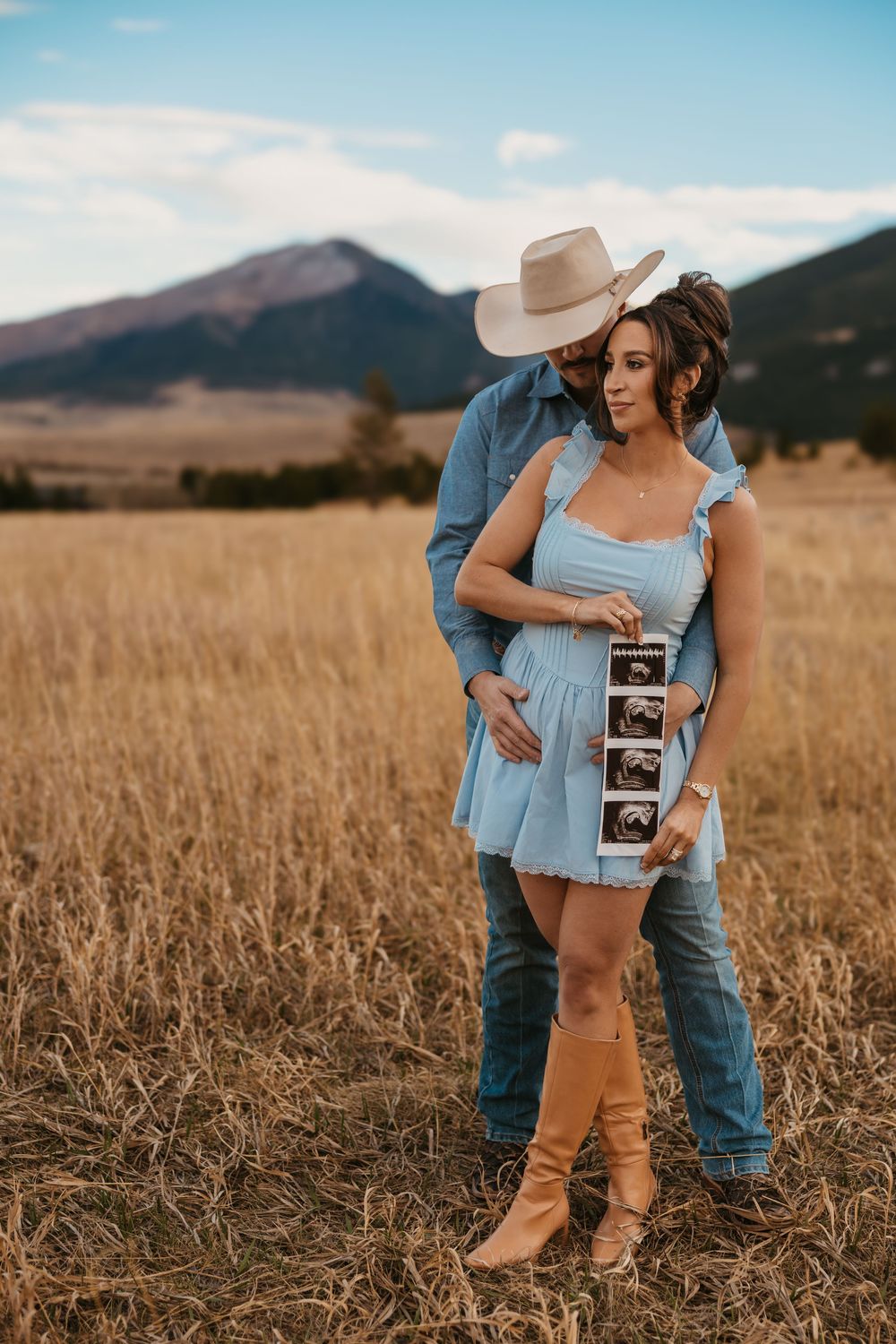 Cowboy holds wife while showing off ultrasound photos in the mountains of Red Lodge, Montana captured by Montana Photographer