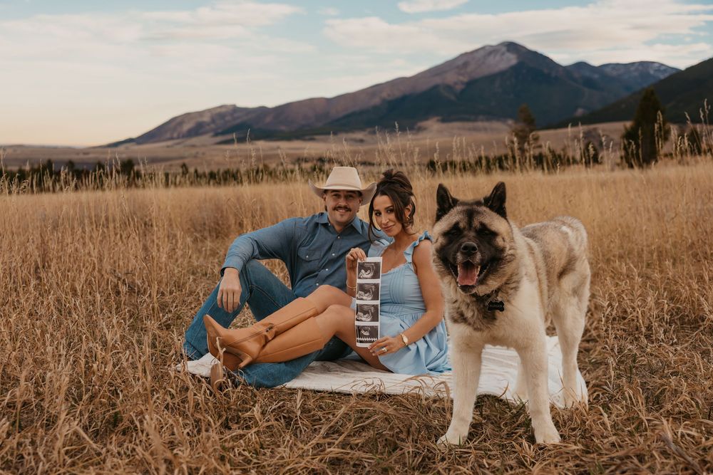 Couple cuddling shows off ultrasound photos with their dog in the mountains of Red Lodge, Montana captured by Montana Photographer