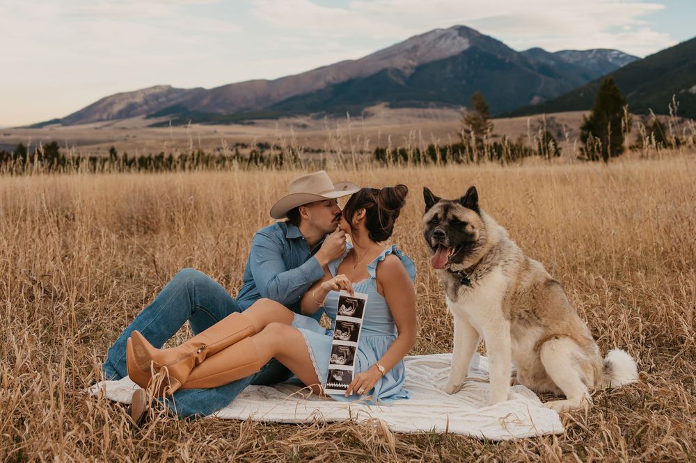 Couple cuddling shows off ultrasound photos with their dog in the mountains of Red Lodge, Montana captured by Montana Photographer