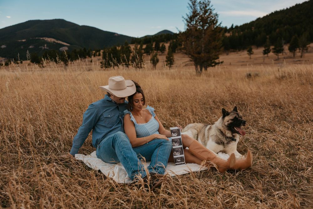 Couple cuddling shows off ultrasound photos with their dog in the mountains of Red Lodge, Montana captured by Montana Photographer