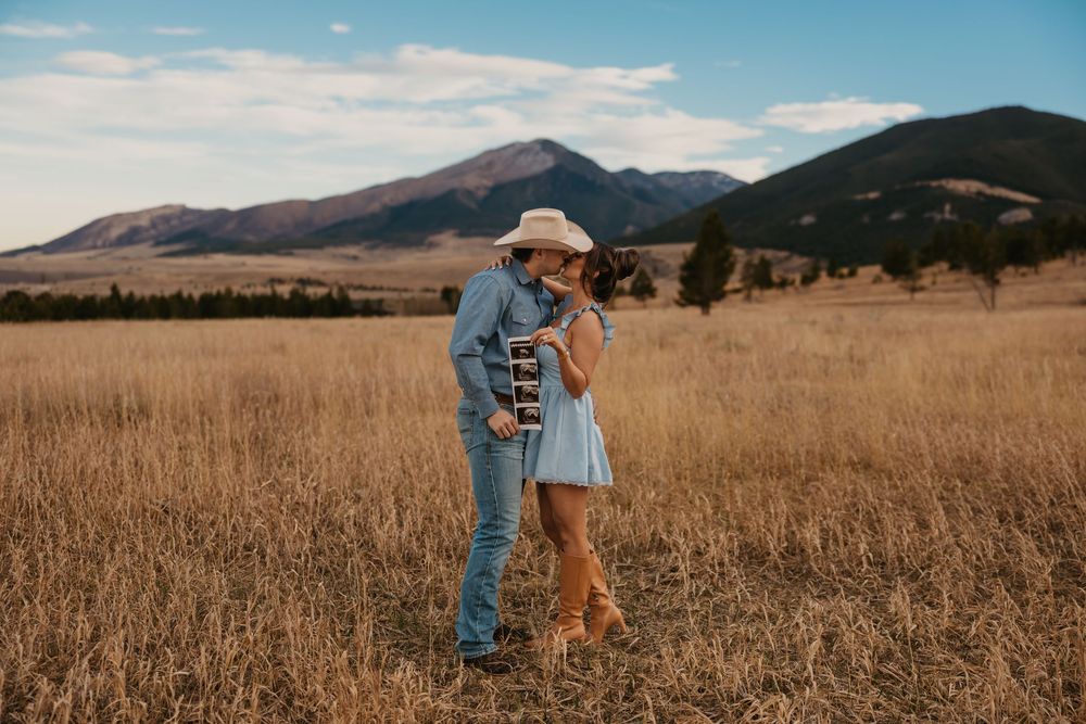 Cowboy holds wife while showing off ultrasound photos in the mountains of Red Lodge, Montana captured by Montana Photographer