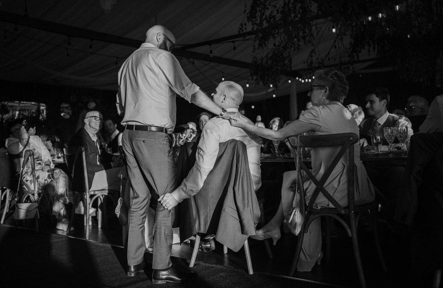 Guests dancing energetically at a wedding reception in black and white photo.