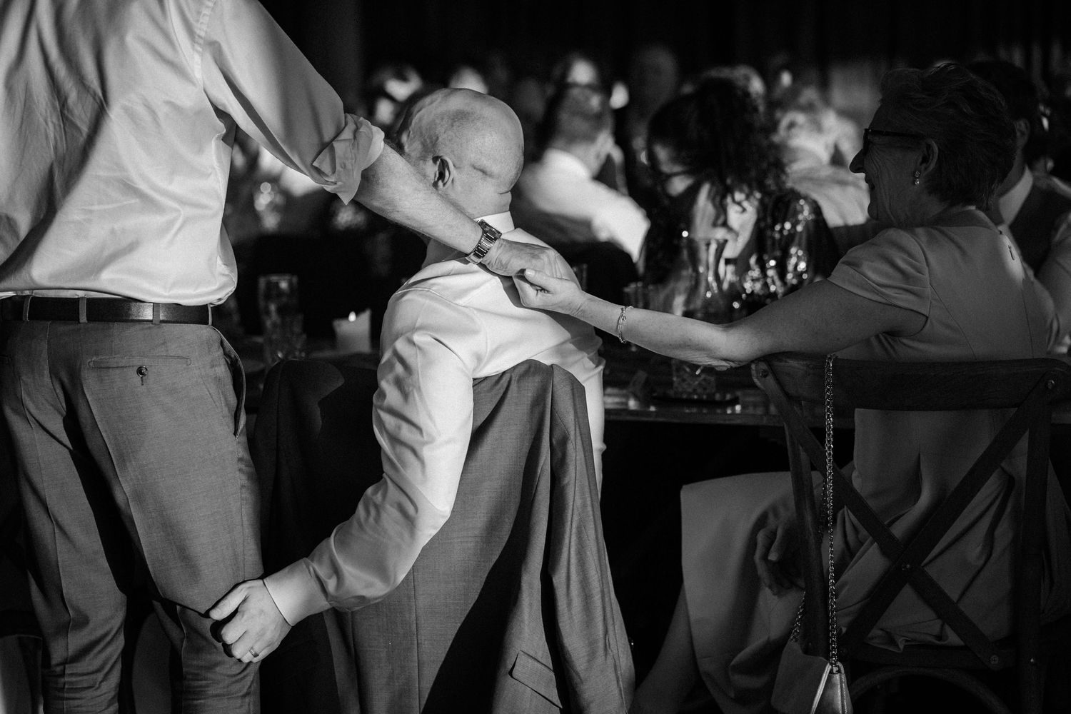 Black and white photo of wedding guest leaning back dramatically on dance floor at reception.