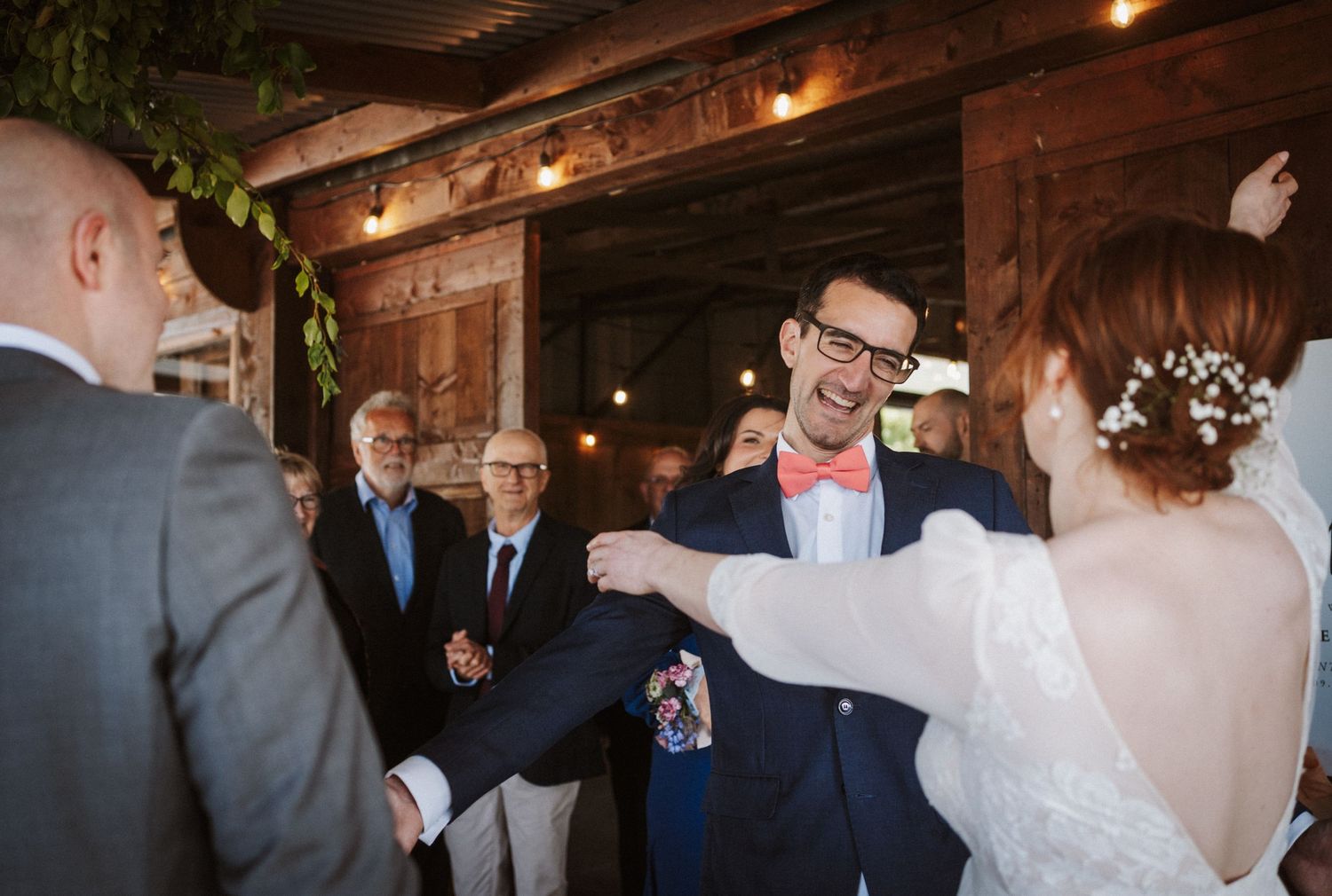 Bride and groom share a joyful moment with guests during a rustic barn wedding ceremony.