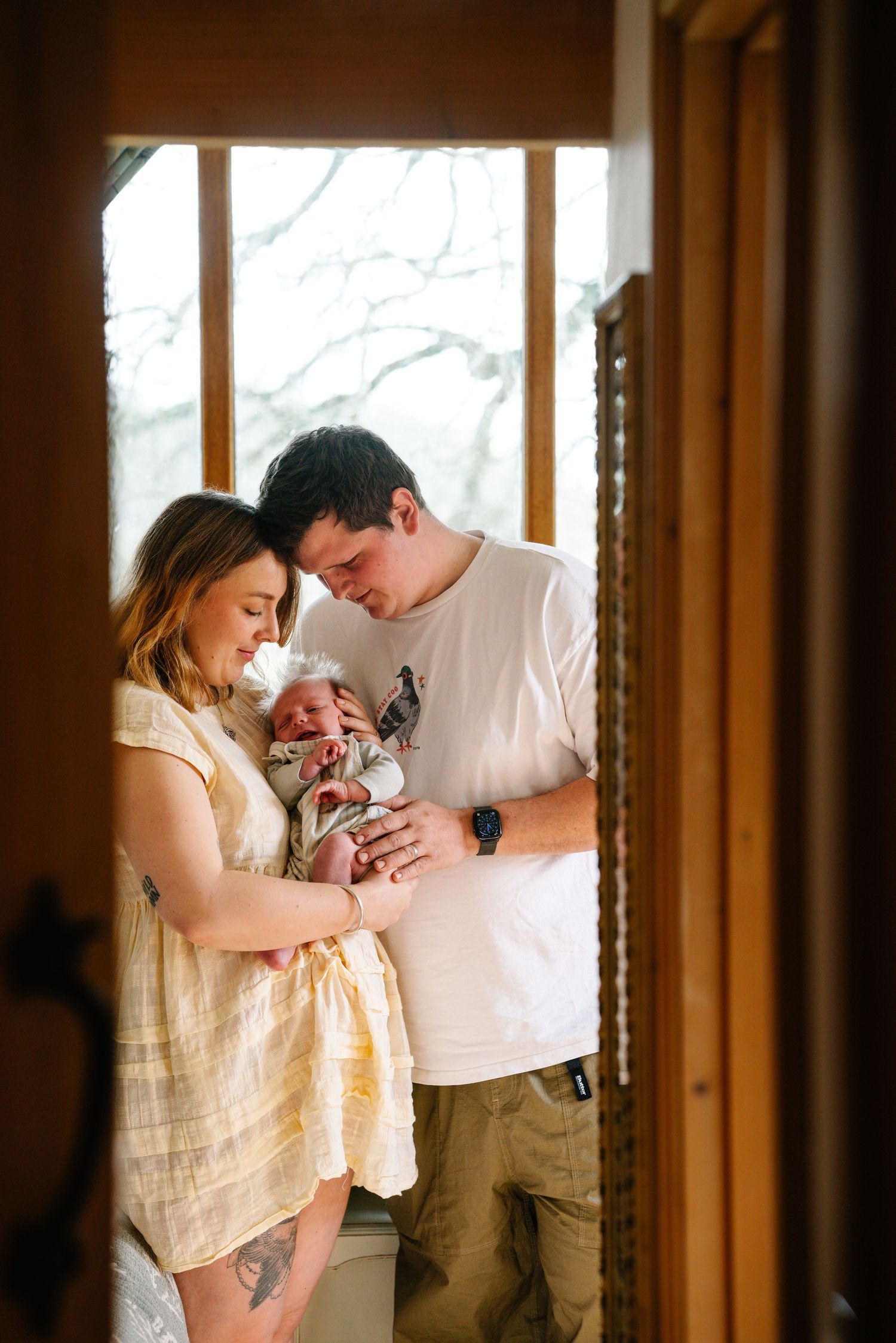 A tender moment as a blonde mother gazes lovingly at her yawning newborn baby cradled in her arms.