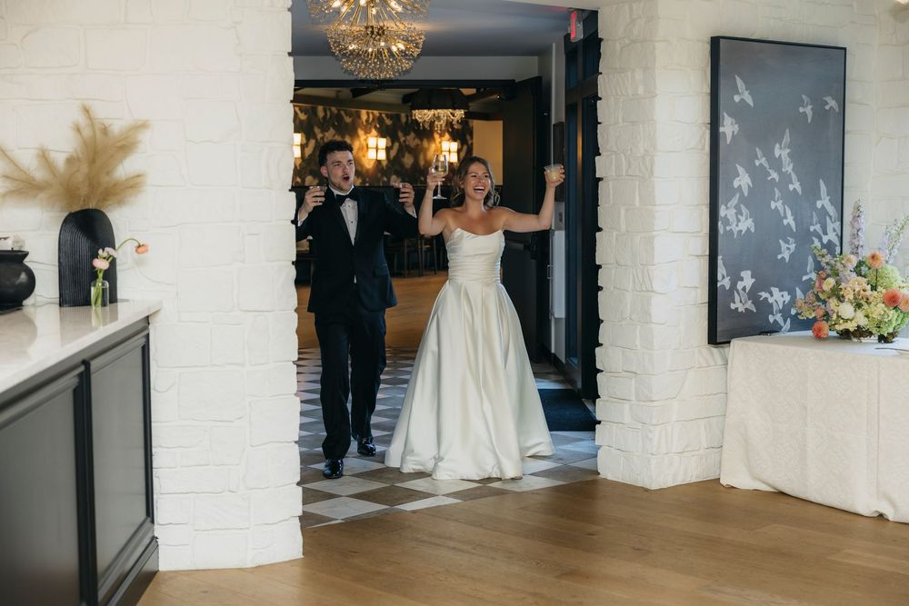 Bride in white ball gown and groom in tuxedo making grand entrance at elegant wedding venue captured by candid photographer in Wisconsin