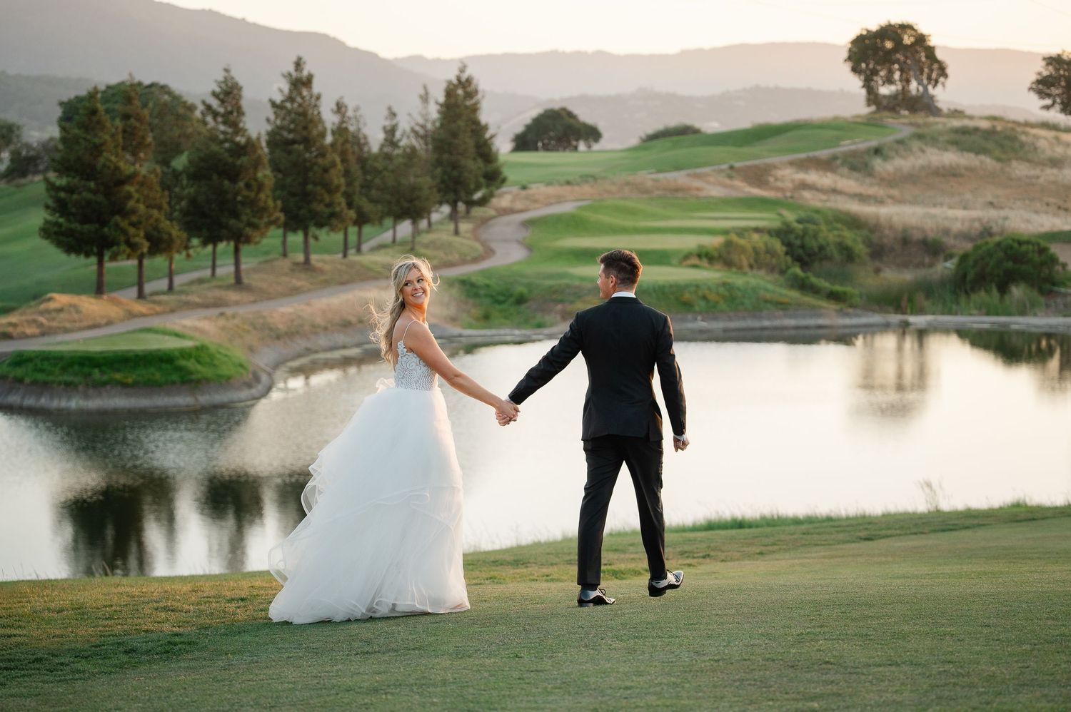 Bride and groom pose in front of cactus garden with golden mountain backdrop at outdoor wedding.