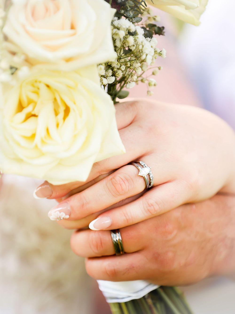 Bride and groom hold flowers and show off their rings
