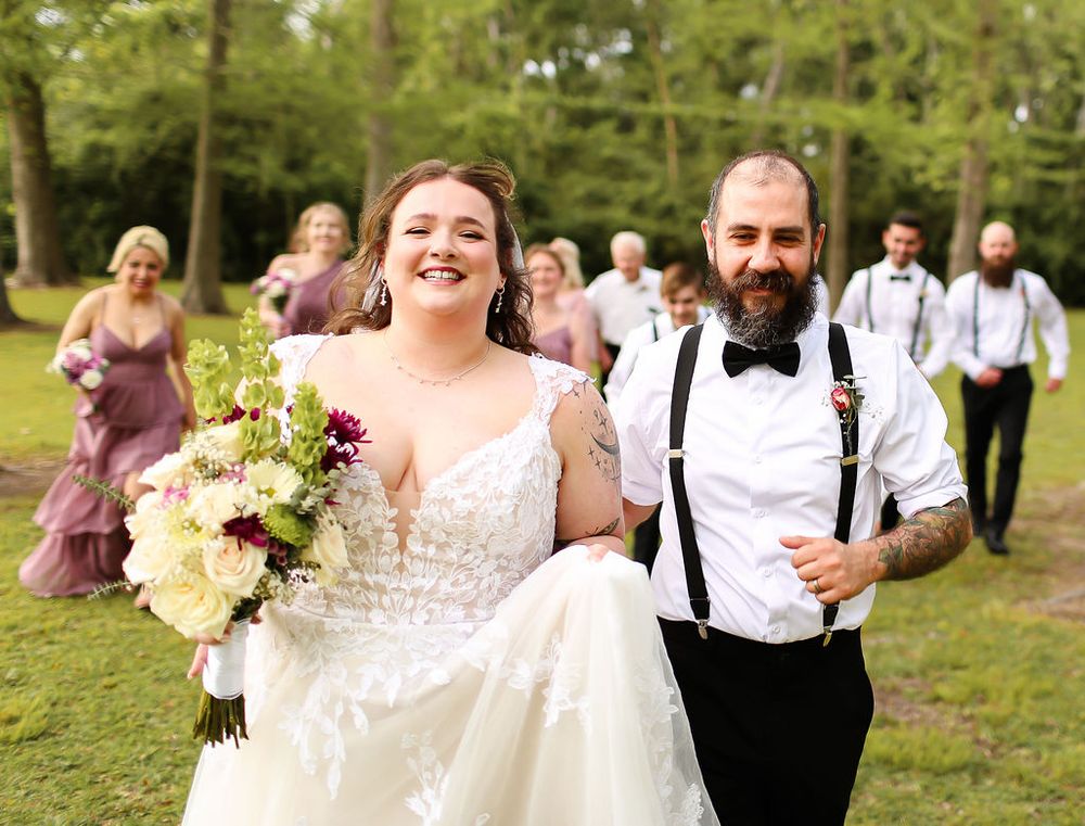 Husband and wife run with their wedding bridal party