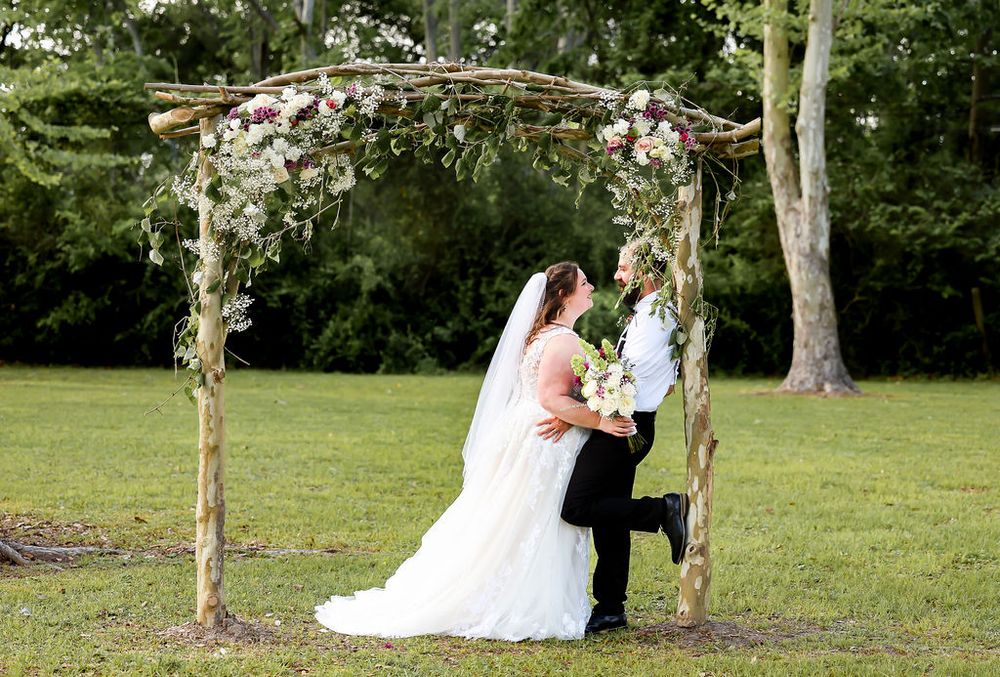 Husband and wife posing under arch on wedding day
