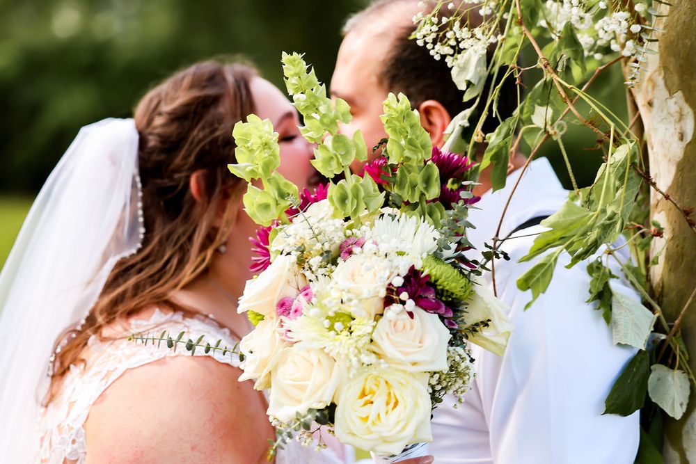 Bride and from kiss behind flower bouquet