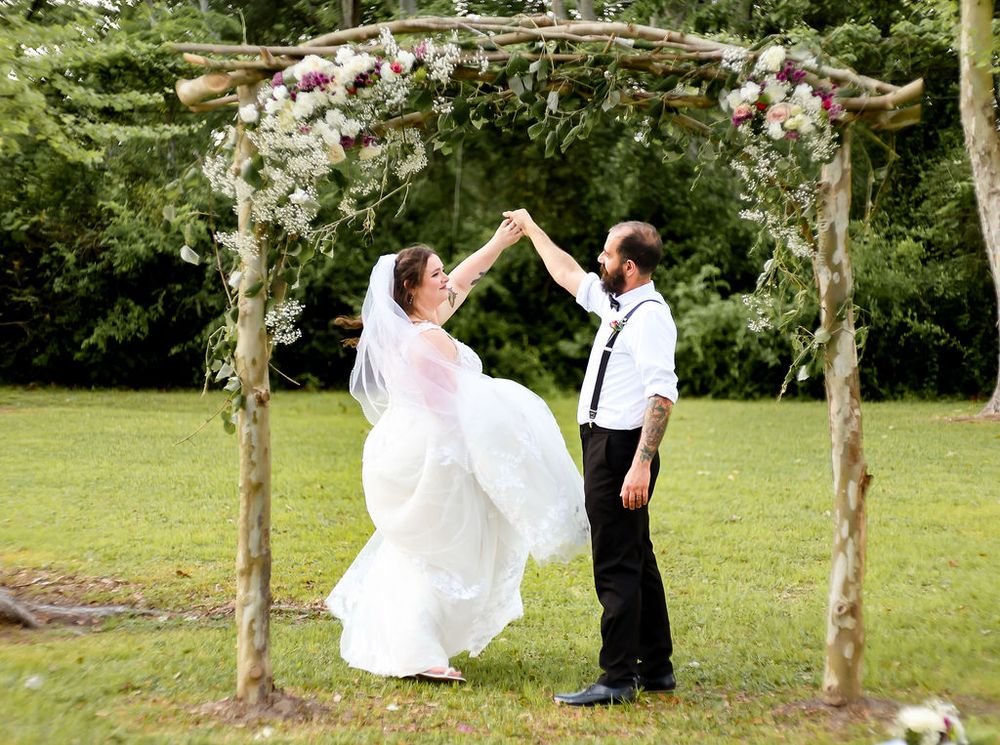 Husband and wife dancing under arch after saying I do